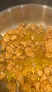 Seasoned chicken pieces cooking in a skillet